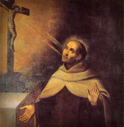 Oil painting of Saint John of the Cross in a brown Carmelite habit, gazing upward at a crucifix from which rays of light radiate toward him.