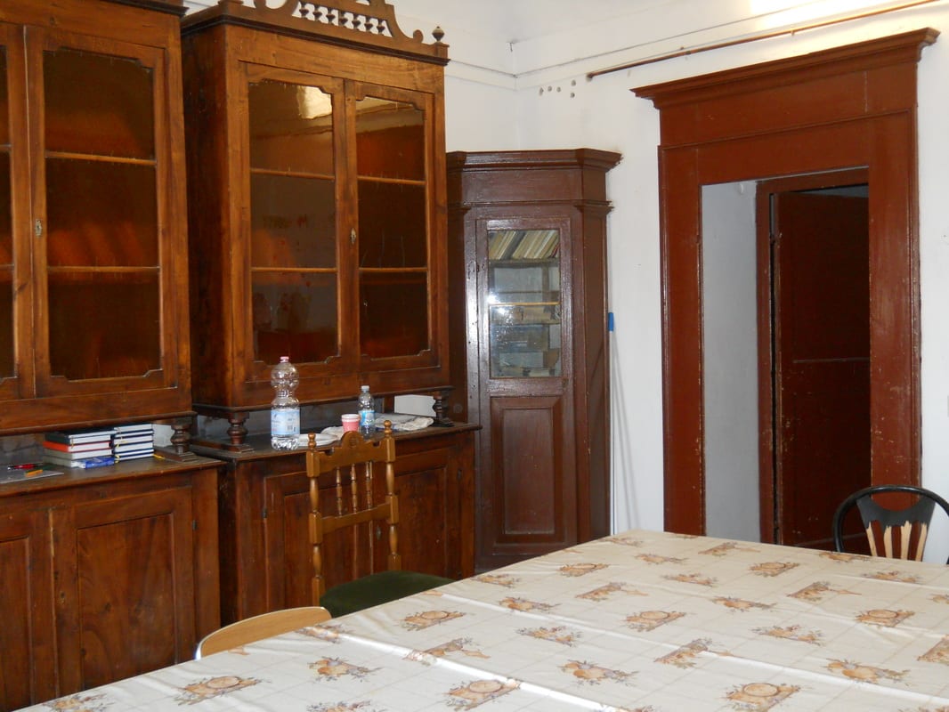 Tall wooden bookcases with glass doors lining one wall, a long table in the foreground, and a corner cabinet near the doorway.