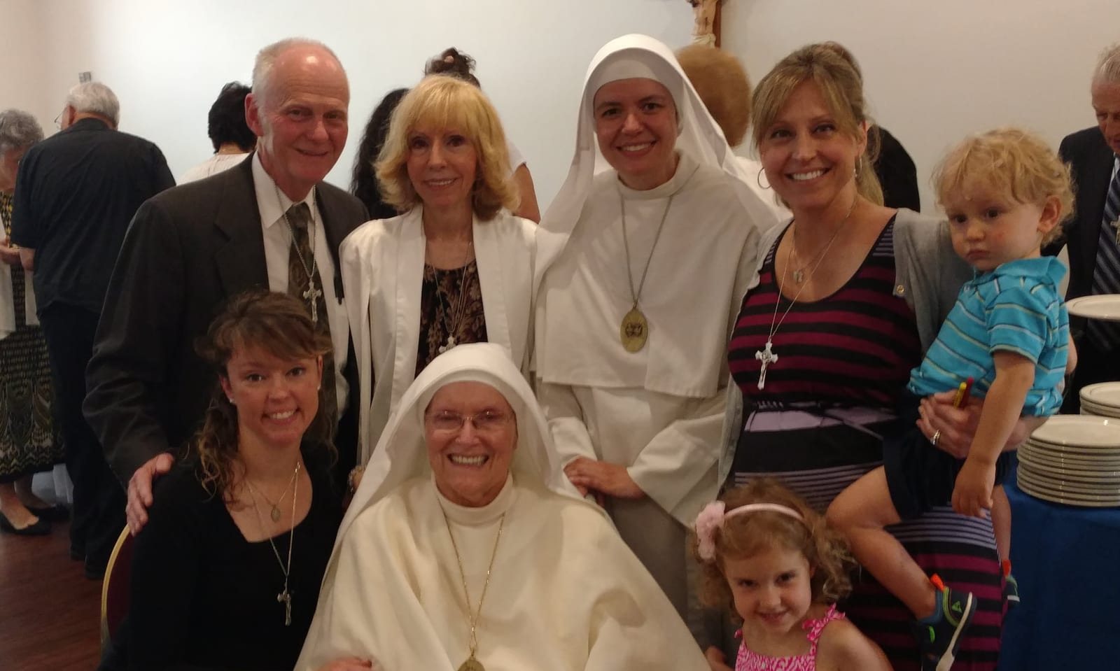 Two sisters with a family of adults and young children, gathered together indoors for a photograph.