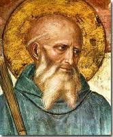 Detail of a fresco depicting Saint Benedict of Nursia, bearded, with golden halo and staff, looking to one side.
