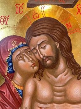 Close-up detail of a Byzantine icon showing Christ and the Virgin Mary cheek to cheek on a gold background, with Greek letters visible.