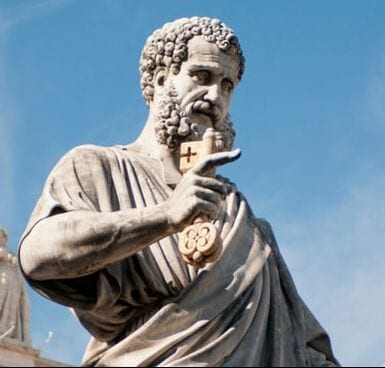 Marble statue of Saint Peter holding a key and raising two fingers in blessing, set against a blue sky.